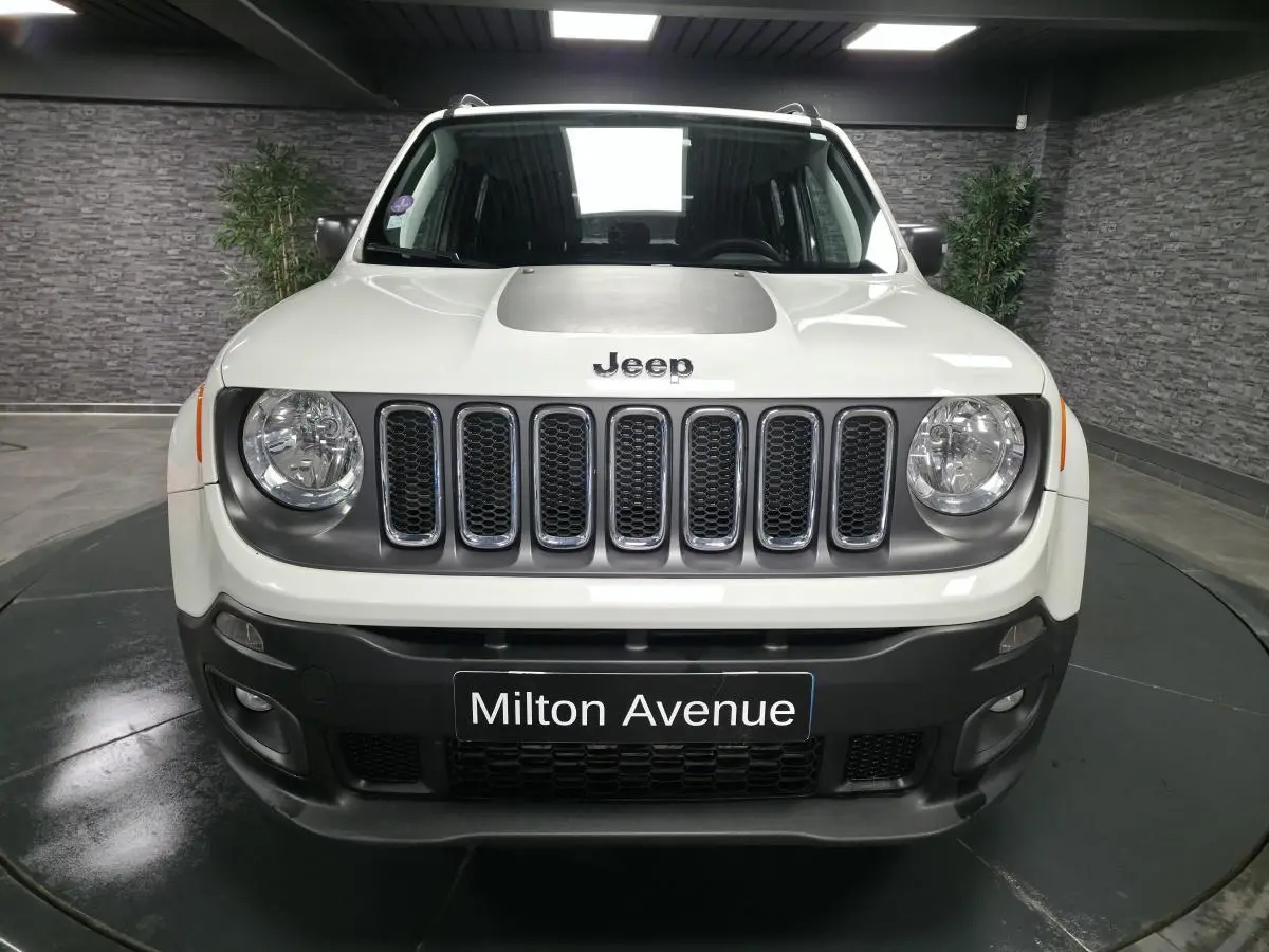 Vue frontale d'un Jeep Renegade blanc avec calandre gris clair et jantes noires cinq branches.