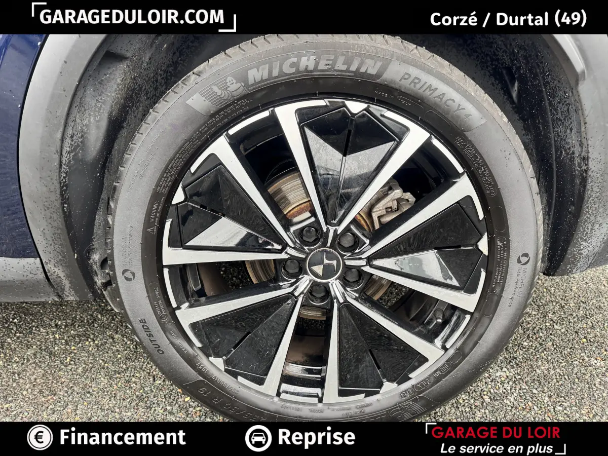 Gros plan sur la jante noire et argentée d’un DS7 Crossback bleu, avec pneu Michelin Primacy 4 visible.