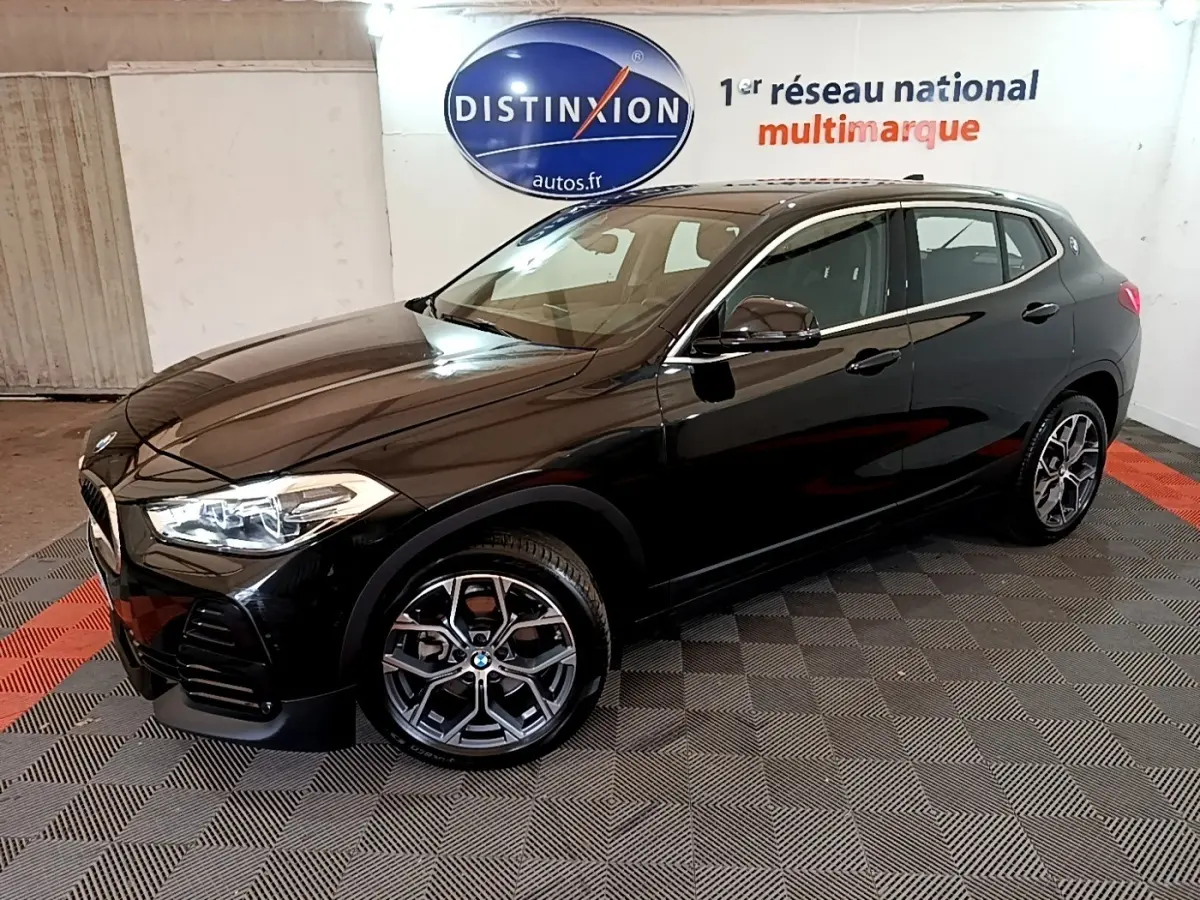 BMW X2 sDrive18i Lounge noire vue 3/4 avant droit dans un showroom avec jantes alliage distinctives.