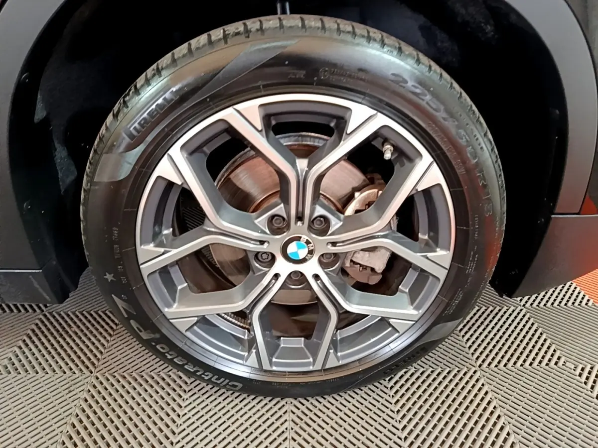 Gros plan sur la roue avant droite noire d’un BMW X2 sDrive18i Lounge 2023 avec jante alliage à design géométrique.