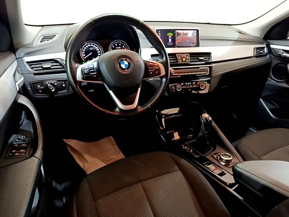 Intérieur BMW X2 sDrive18i 2023 vu de face, volant cuir, tableau de bord avec écran multimédia et levier de vitesse manuel.