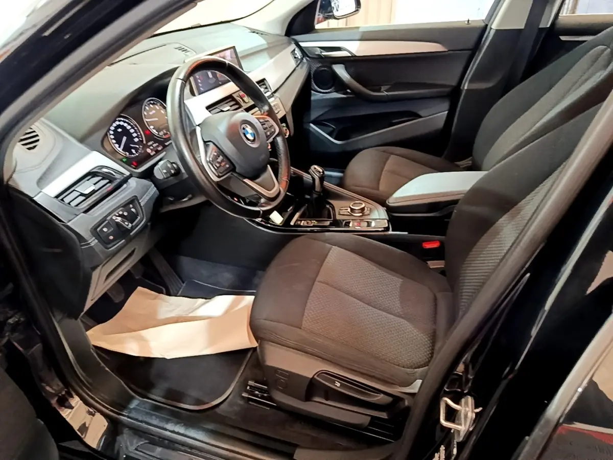 Intérieur noir de la BMW X2 sDrive18i 2023 vu côté conducteur, avec volant cuir et boîte manuelle.