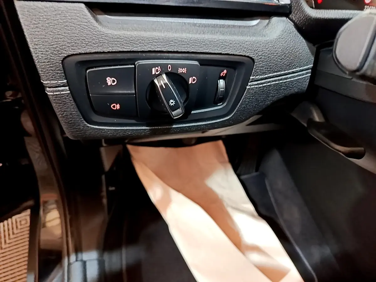 Détail du tableau de bord noir de la BMW X2 sDrive18i 2023 montrant la commande des phares et antibrouillards.