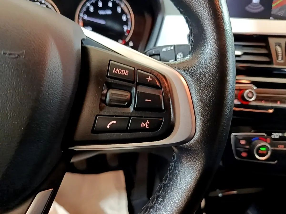 Gros plan sur le volant multifonctions en cuir noir et la console centrale du BMW X2 sDrive18i Lounge 2023.