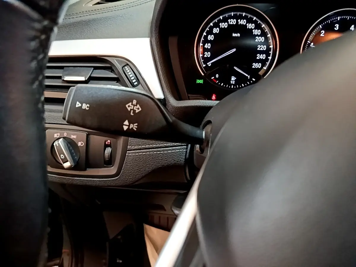 Détail intérieur côté gauche du tableau de bord noir de la BMW X2 sDrive18i Lounge 2023 avec commandes et compteur.