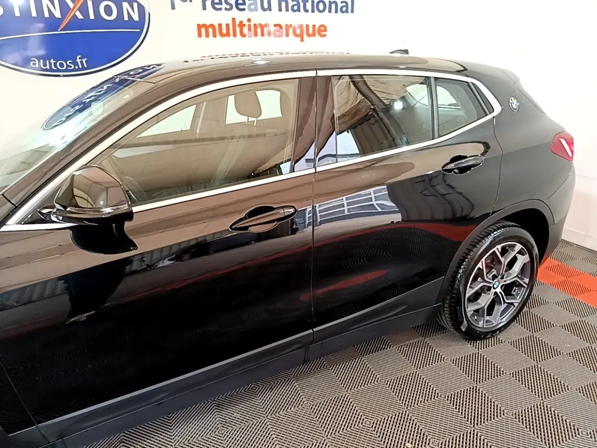 Vue latérale droite d'un BMW X2 sDrive18i Lounge noir brillant, mettant en valeur les jantes et la ligne de caisse élégante.