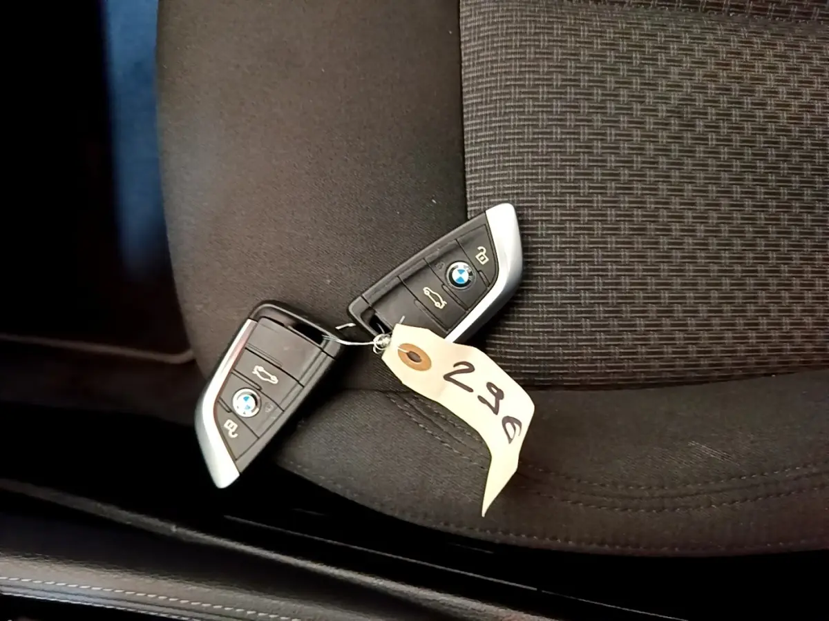 Gros plan sur deux clés BMW posées sur un siège tissu noir avec étiquette numérotée 298.