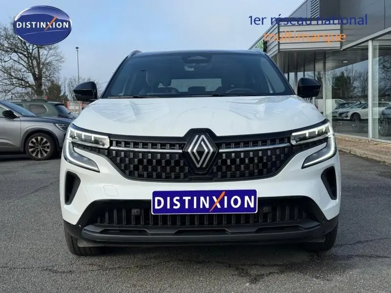 Vue frontale du Renault Austral 2025 blanc nacré avec toit noir étoilé, mettant en valeur sa calandre noire et ses phares LED distinctifs.