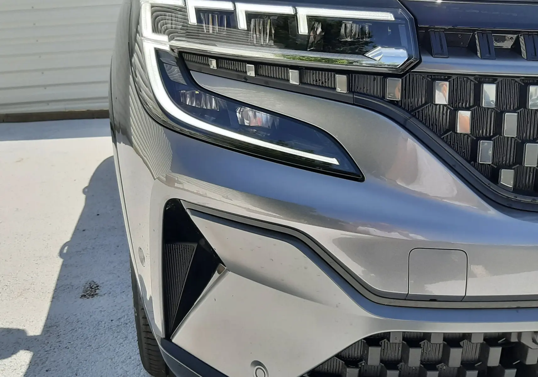 Gros plan sur le phare avant gauche du Renault Espace VI gris schiste métal, soulignant la calandre et les détails LED.