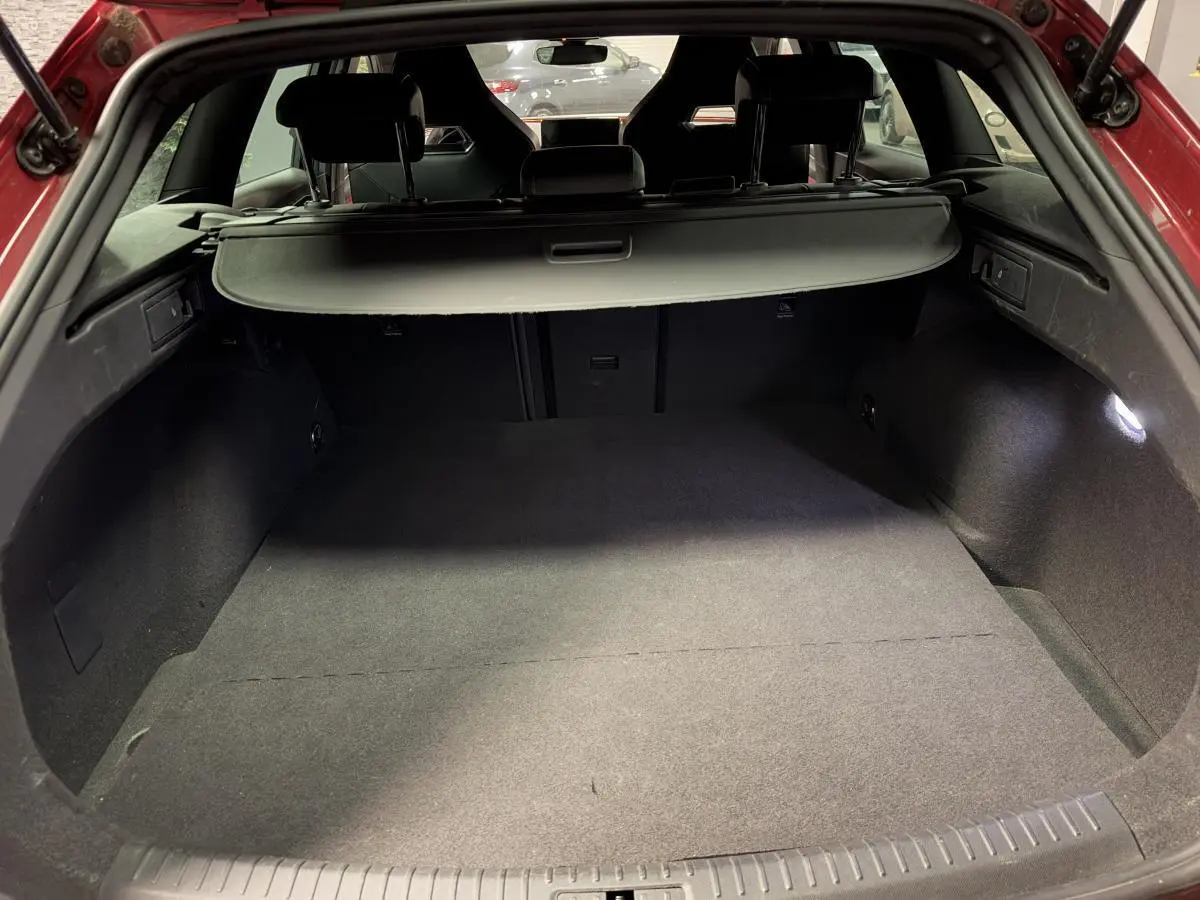 Coffre ouvert d'une CUPRA Leon Sportstourer rouge, vue arrière montrant l'espace de chargement avec cache-bagages noir.