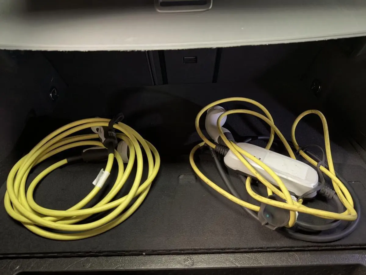 Gros plan sur le coffre d'une CUPRA Leon Sportstourer rouge avec câbles de recharge hybride jaune enroulés.