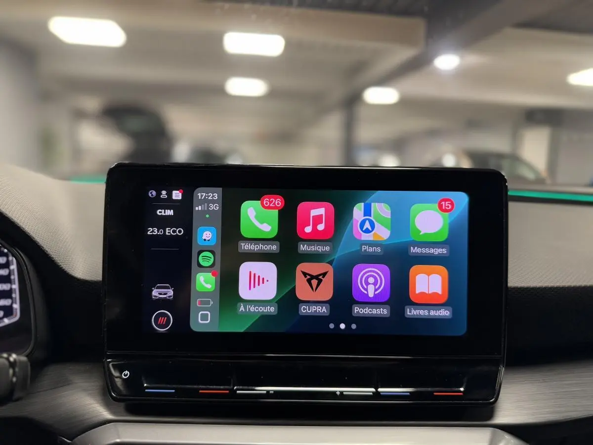 Écran tactile central affichant Apple CarPlay dans l'habitacle d'une CUPRA Leon Sportstourer rouge, vue de face.