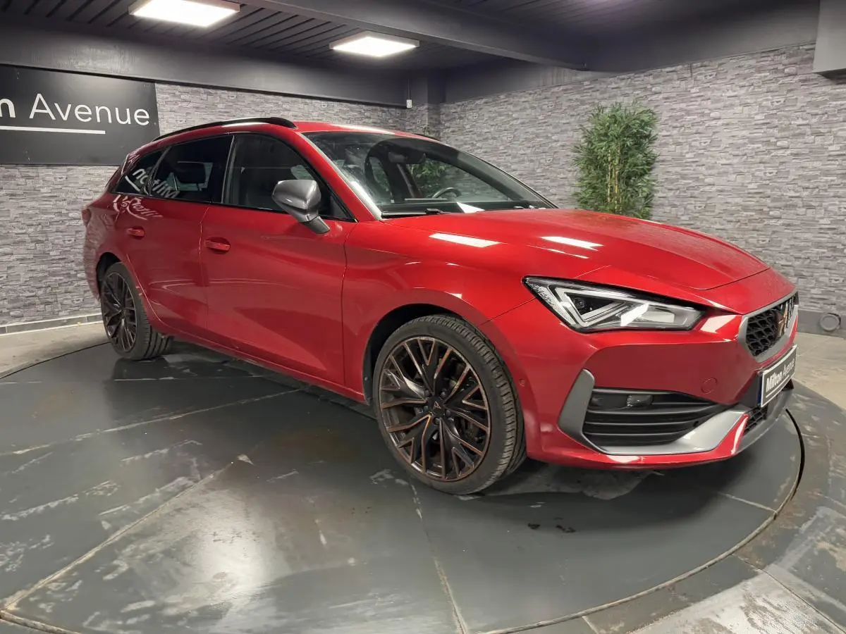 Vue 3/4 avant d'une CUPRA Leon Sportstourer rouge Désir avec jantes alliage noires et rétroviseurs gris.