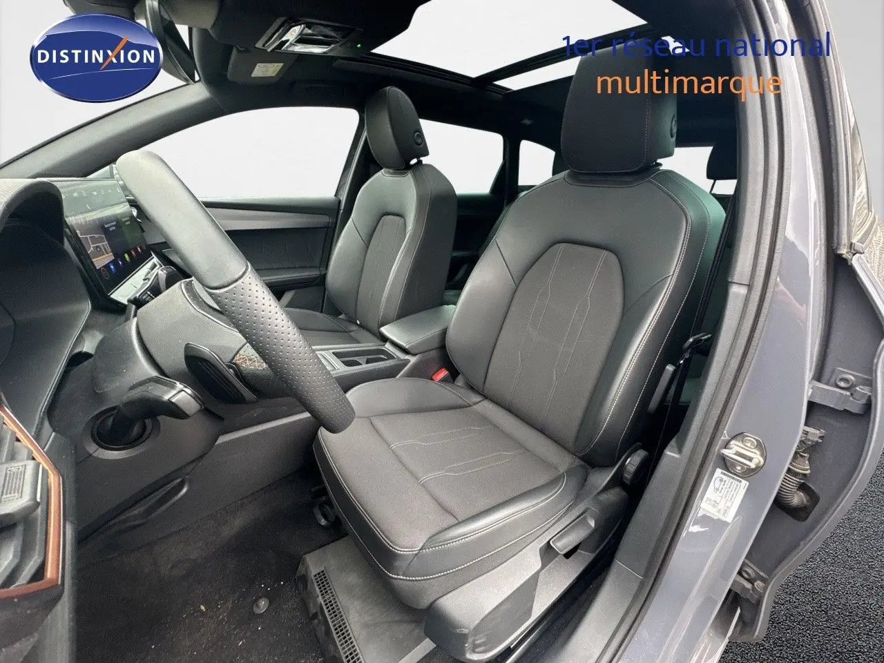 Vue intérieure côté conducteur de la CUPRA LEON ST gris Graphene avec sièges en cuir noir et tableau de bord moderne.