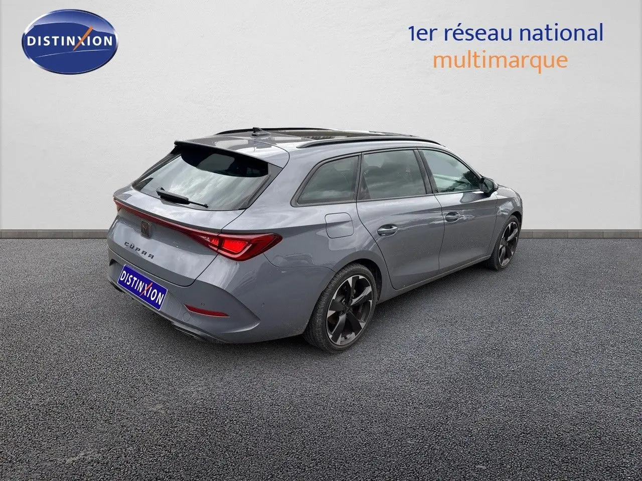 Vue 3/4 arrière droite d'une CUPRA LEON ST gris Graphene metal avec jantes noires bicolores sur fond neutre.