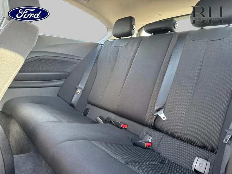 Vue intérieure de la banquette arrière noire de la BMW Série 1 114i Lounge 3 portes, avec ceintures de sécurité visibles.