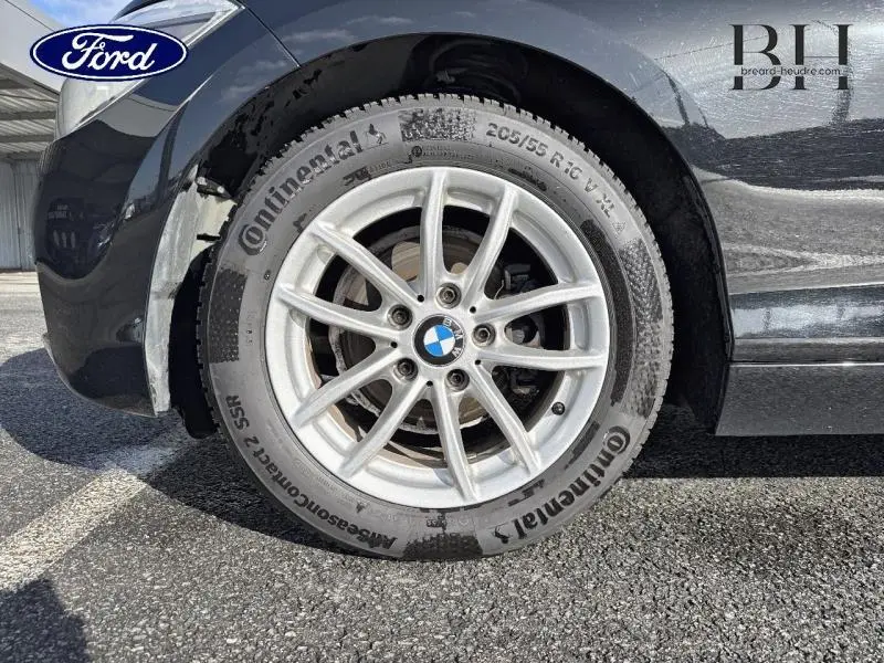 Gros plan sur la roue avant droite d'une BMW Série 1 noire avec jante alu 16 pouces et pneu Continental.