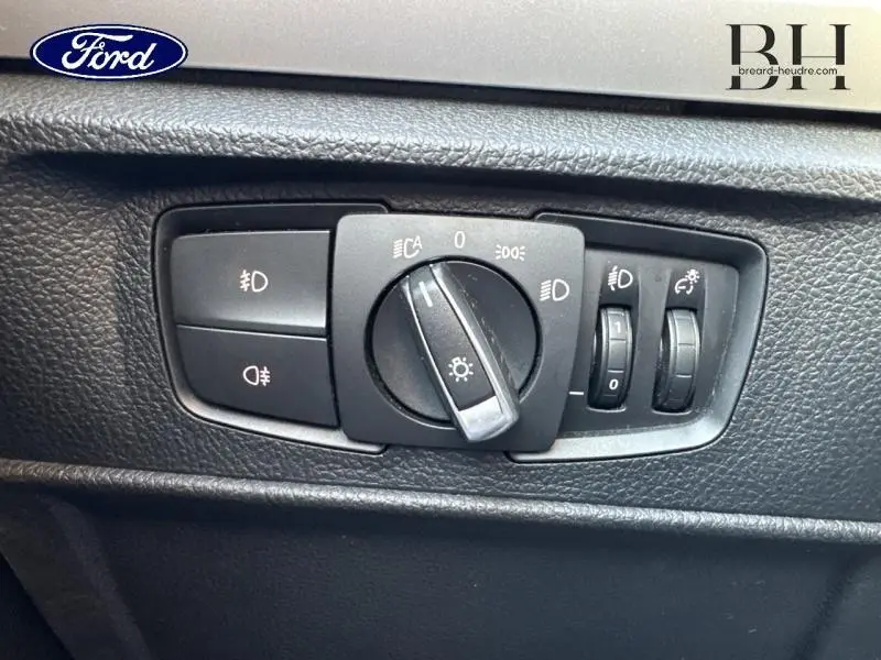 Commande des phares et réglages d'éclairage intérieur d'une BMW Série 1 114i noire, vue en gros plan.