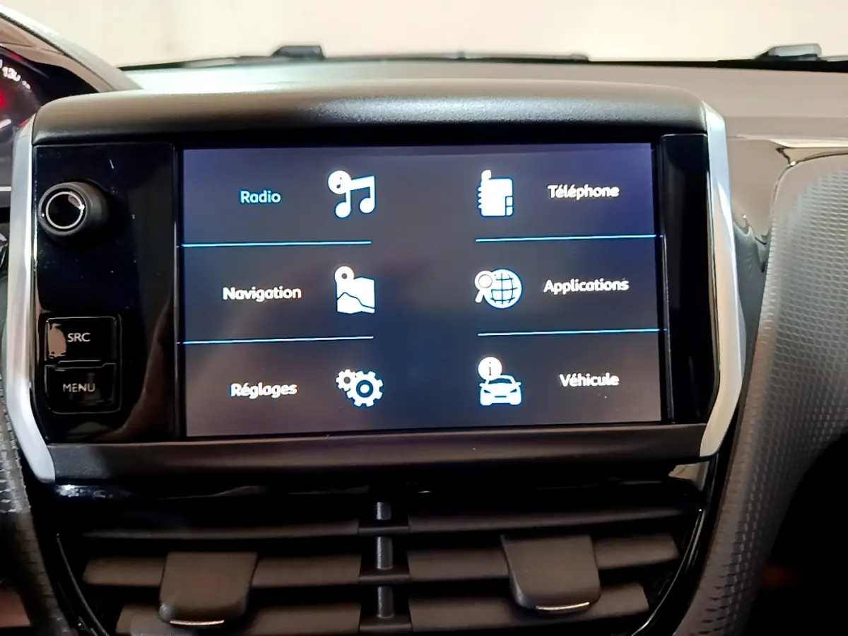 Écran tactile central affichant les menus radio, navigation et téléphone dans l'habitacle d'une Peugeot 2008 gris foncé.
