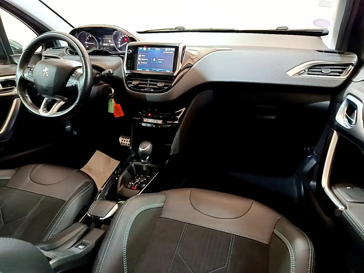 Intérieur de la Peugeot 2008 gris foncé, vue de face montrant le tableau de bord avec écran tactile et volant cuir multifonctions.