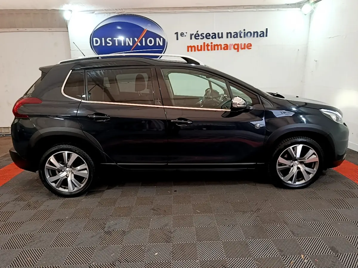 Profil côté gauche d'un Peugeot 2008 gris foncé Crossway de 2019, avec jantes alliage et barres de toit chromées visibles.