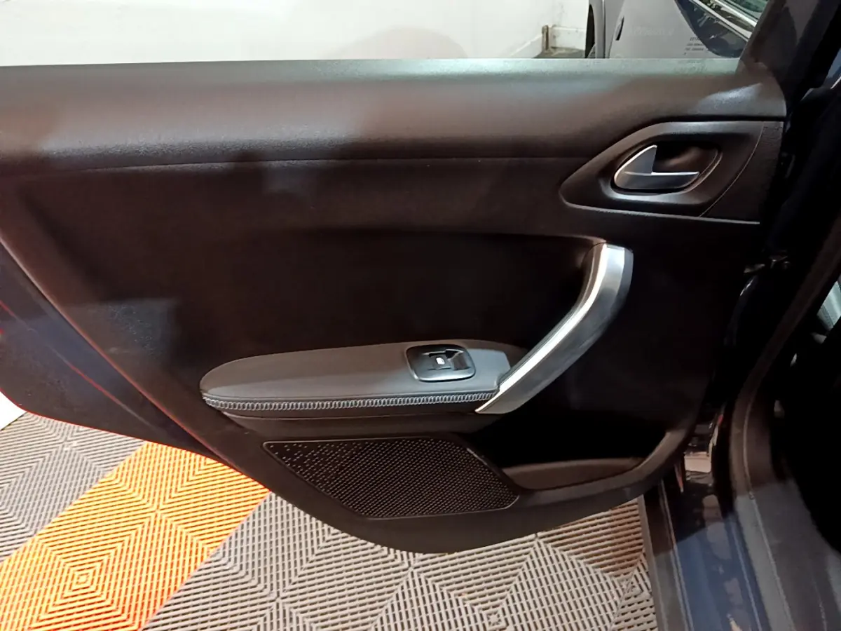 Vue rapprochée de la porte avant droite noire du Peugeot 2008 gris foncé avec poignée argentée et commande de vitre.