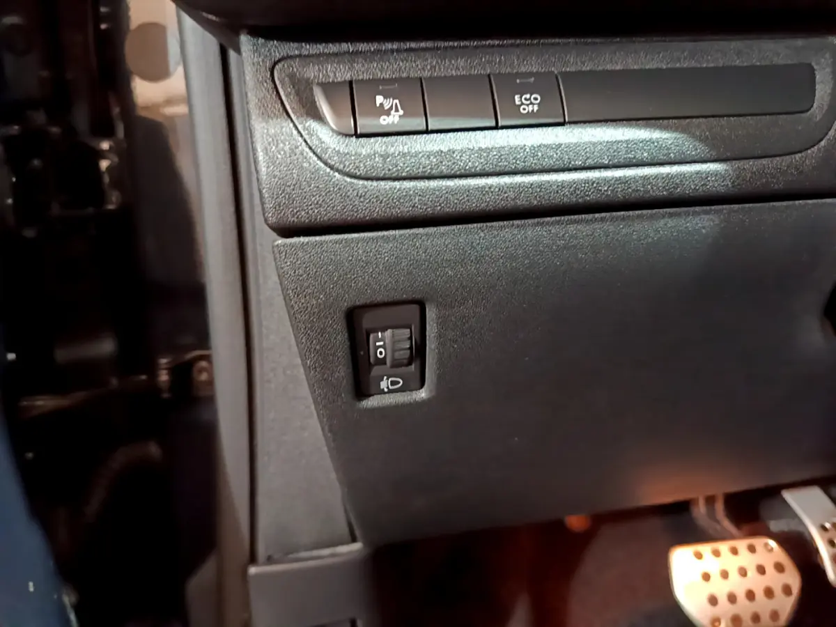 Détail du tableau de bord côté gauche du Peugeot 2008 gris foncé, avec commandes d'éclairage et pédales en aluminium.
