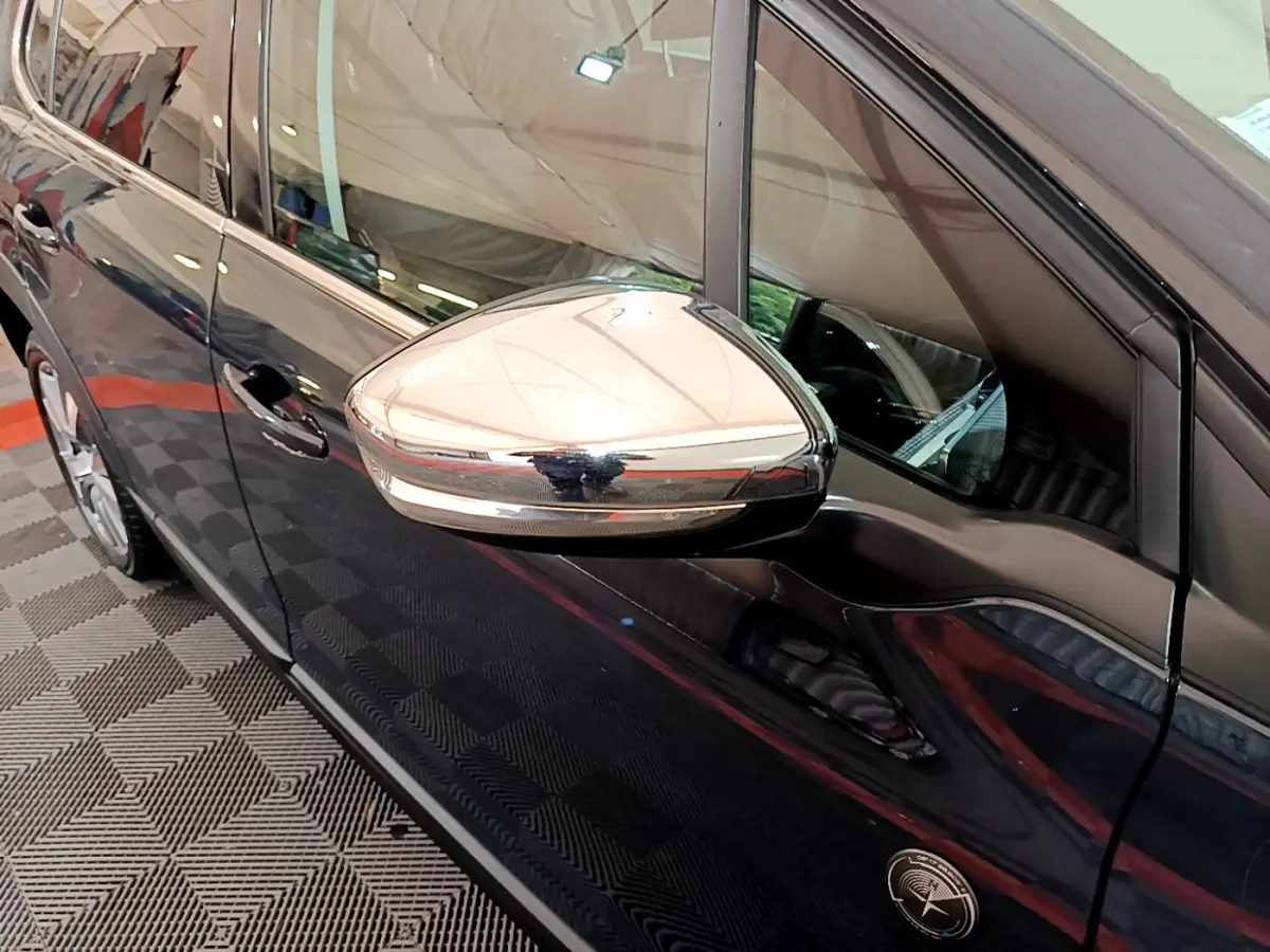 Rétroviseur chromé côté gauche d'un Peugeot 2008 gris foncé, vue rapprochée sur la porte avant.