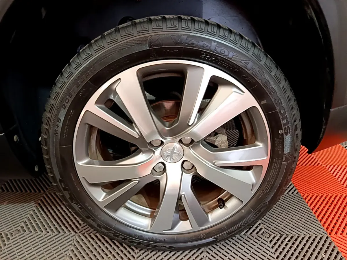 Gros plan sur la roue arrière droite d'un Peugeot 2008 gris foncé, montrant le pneu et l'arche de roue.