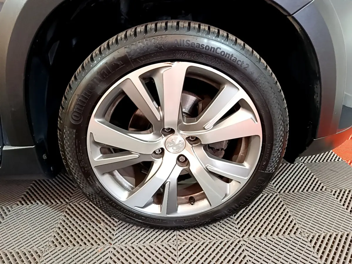 Gros plan sur la roue avant droite du Peugeot 2008 gris foncé, avec jante alliage à cinq branches doubles.