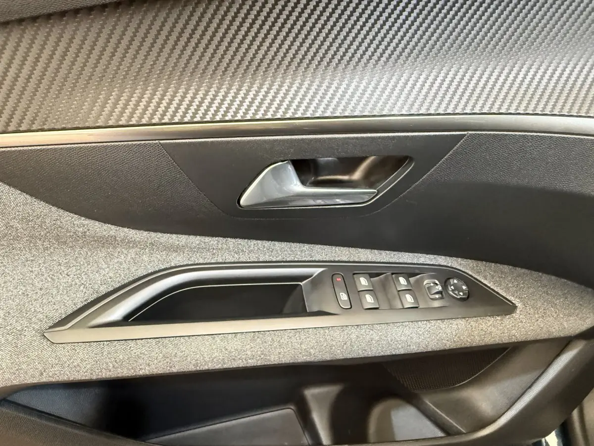 Gros plan sur la porte intérieure côté conducteur du Peugeot 3008 bleu, avec commandes de vitres et poignée argentée.