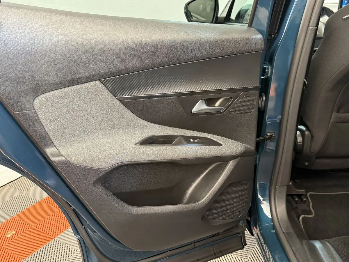 Vue intérieure de la porte arrière gauche bleu métallisé du Peugeot 3008 avec garniture tissu et plastique noir.