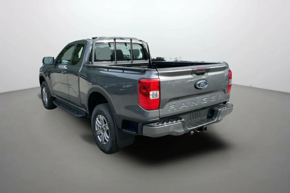Ford Ranger gris carbone vu en 3/4 arrière droit, avec benne ouverte et barre de protection arrière visible.