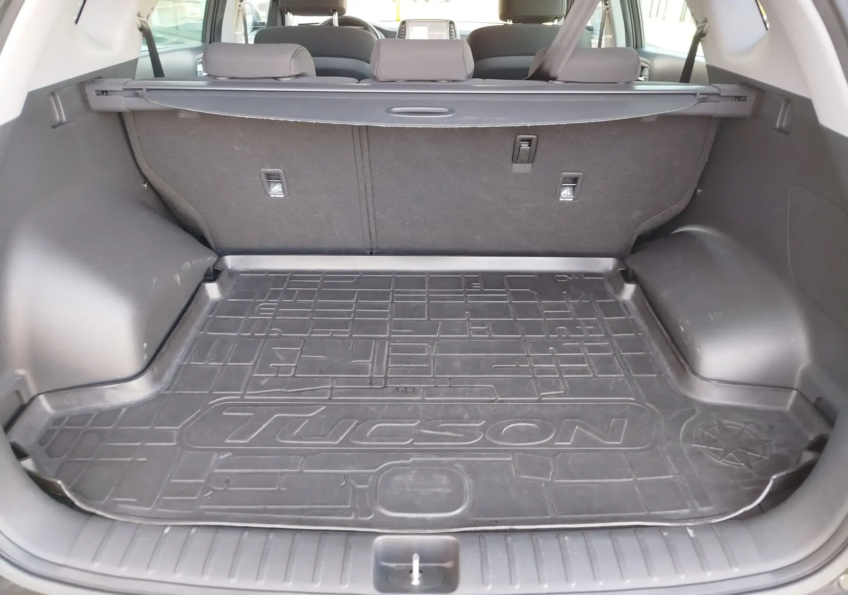 Vue intérieure du coffre du Hyundai Tucson 2019 avec tapis de protection noir marqué Tucson, banquette arrière visible.
