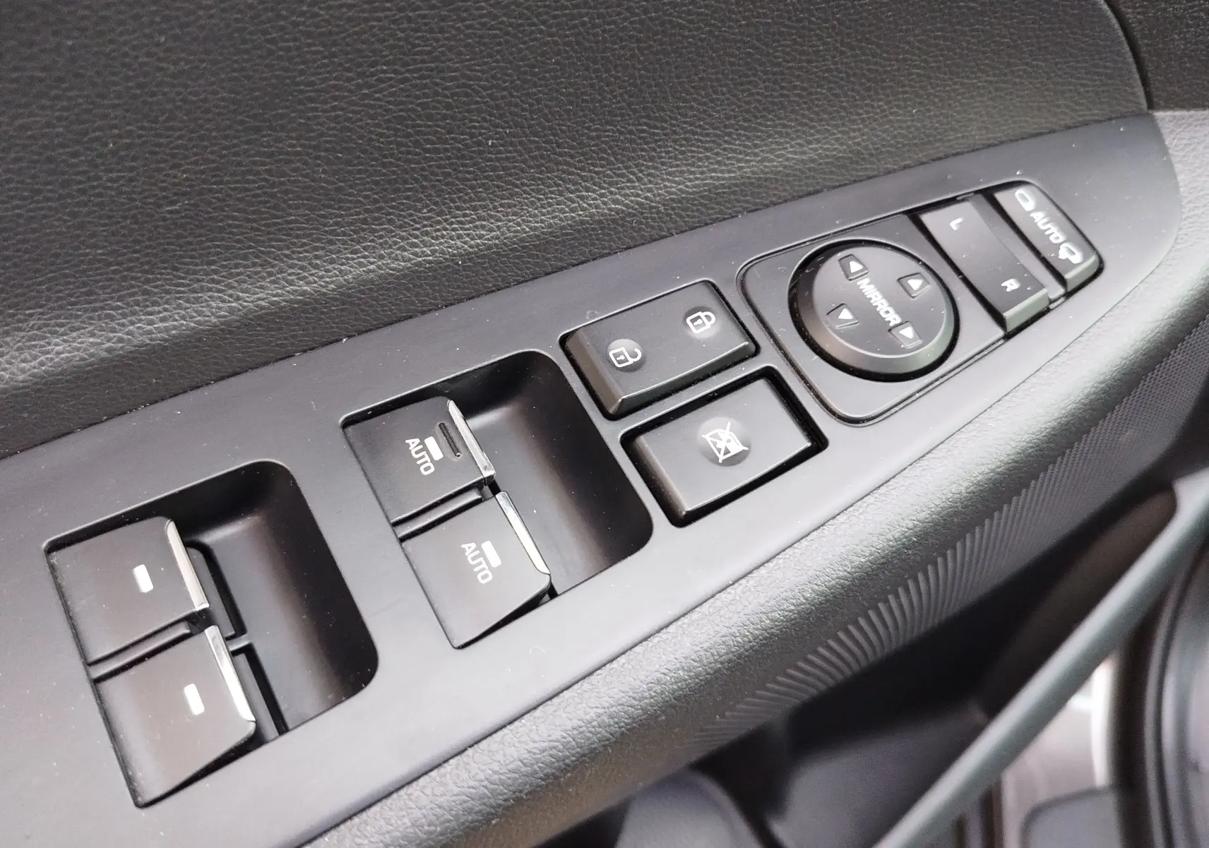 Gros plan sur les commandes de lève-vitres et réglages des rétroviseurs côté conducteur d’un Hyundai Tucson gris Micron 2019.