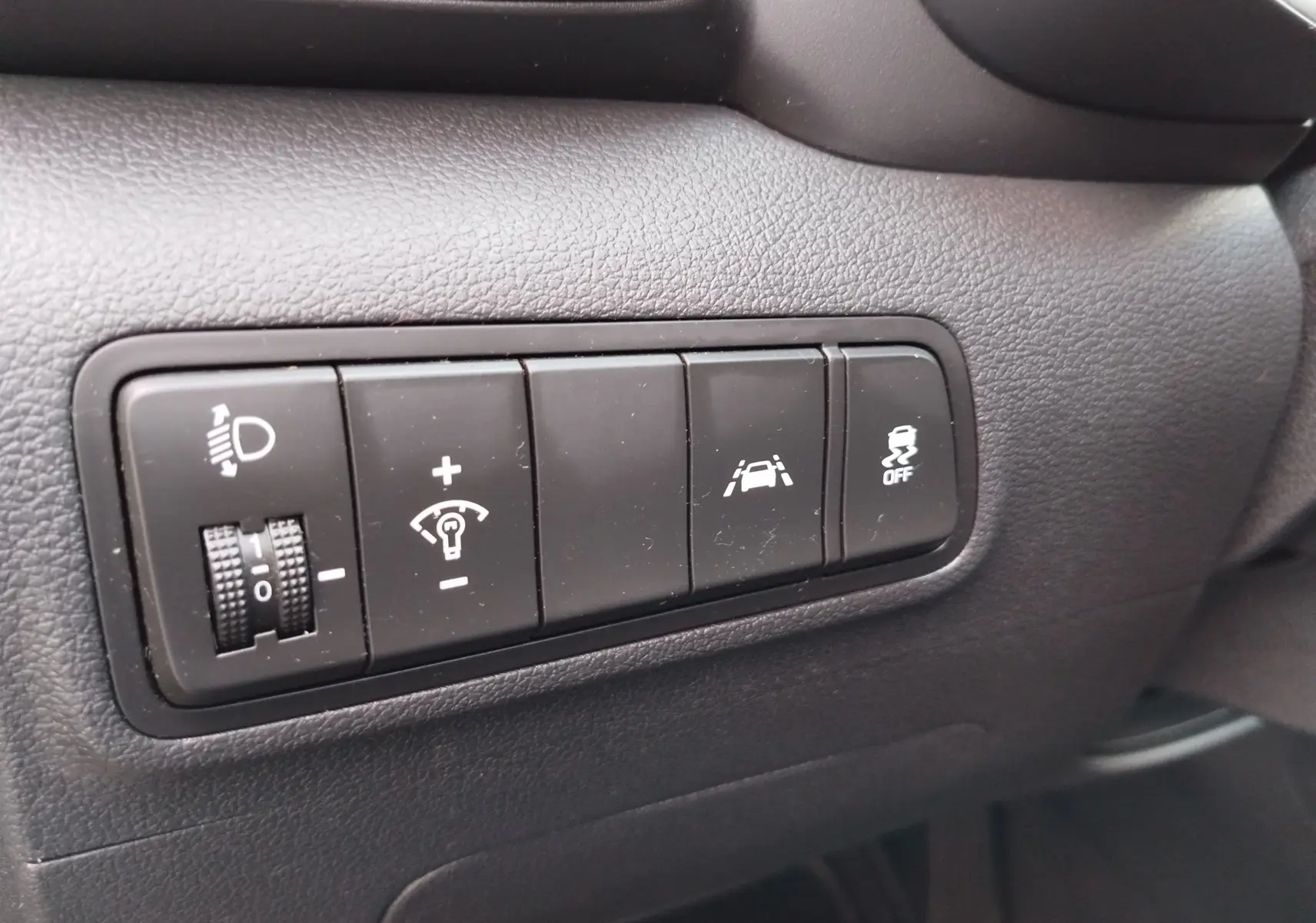 Gros plan sur les boutons de réglage d'éclairage et d'assistance à la conduite du tableau de bord gris foncé du Hyundai Tucson 2019.