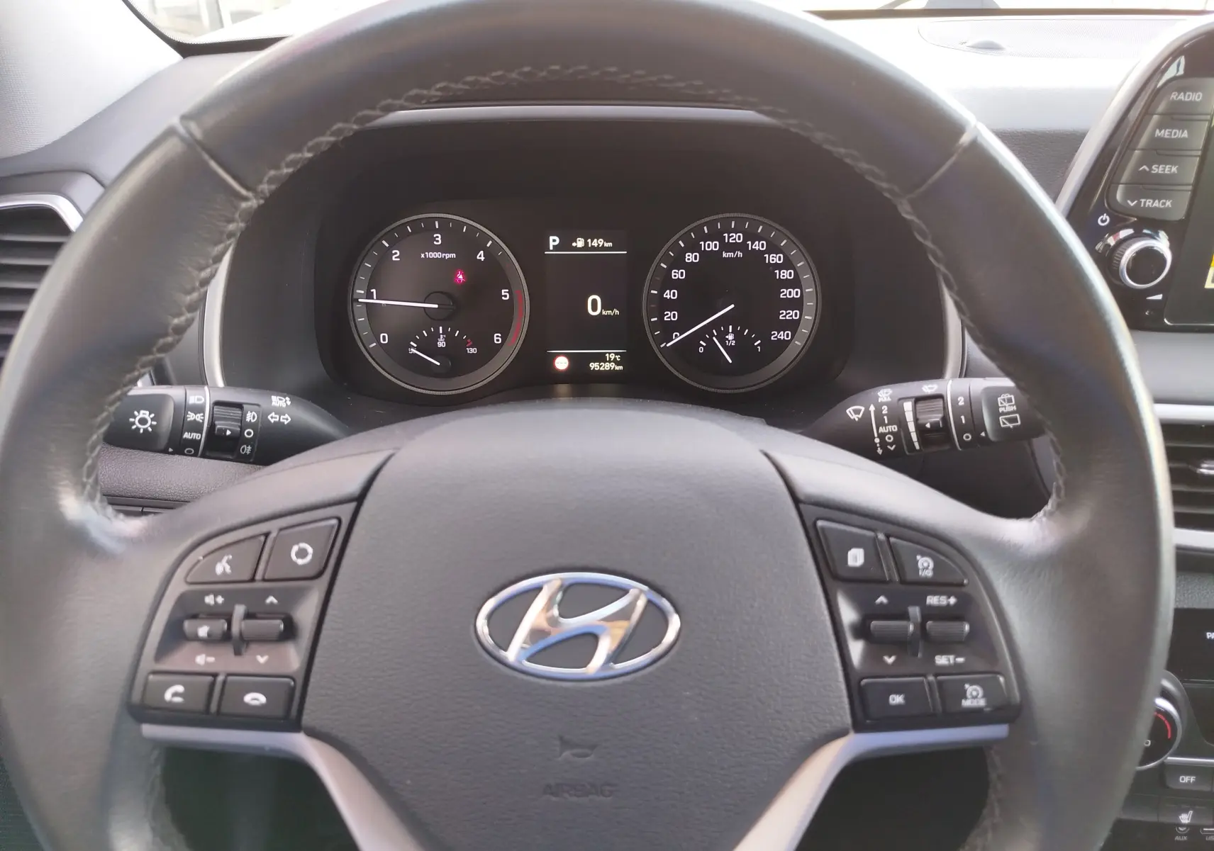 Vue intérieure centrée sur le volant cuir noir du Hyundai Tucson 2019 avec tableau de bord et commandes au volant visibles.