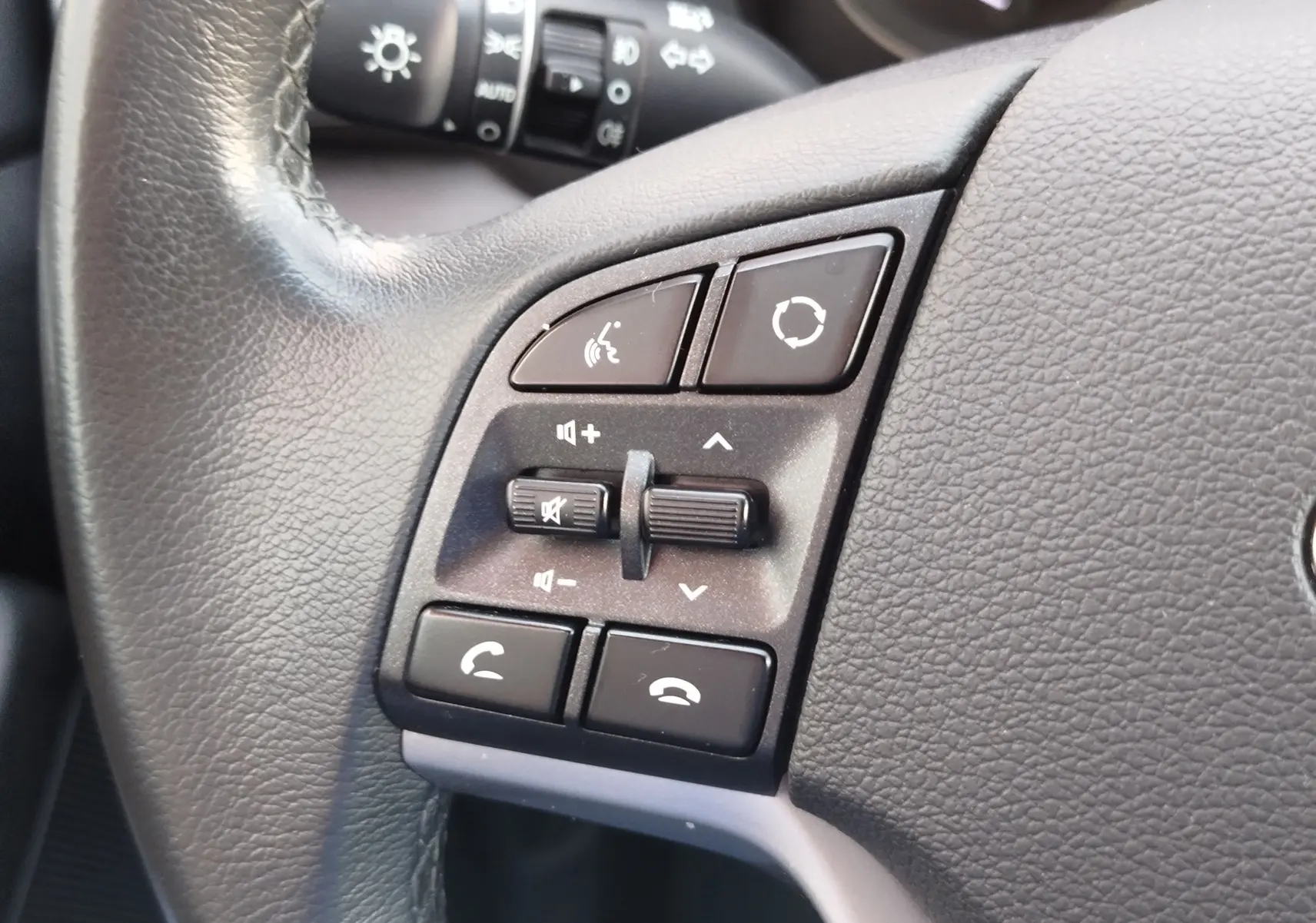 Gros plan sur les commandes du volant en cuir noir du Hyundai Tucson 2019, avec boutons de volume et appels.