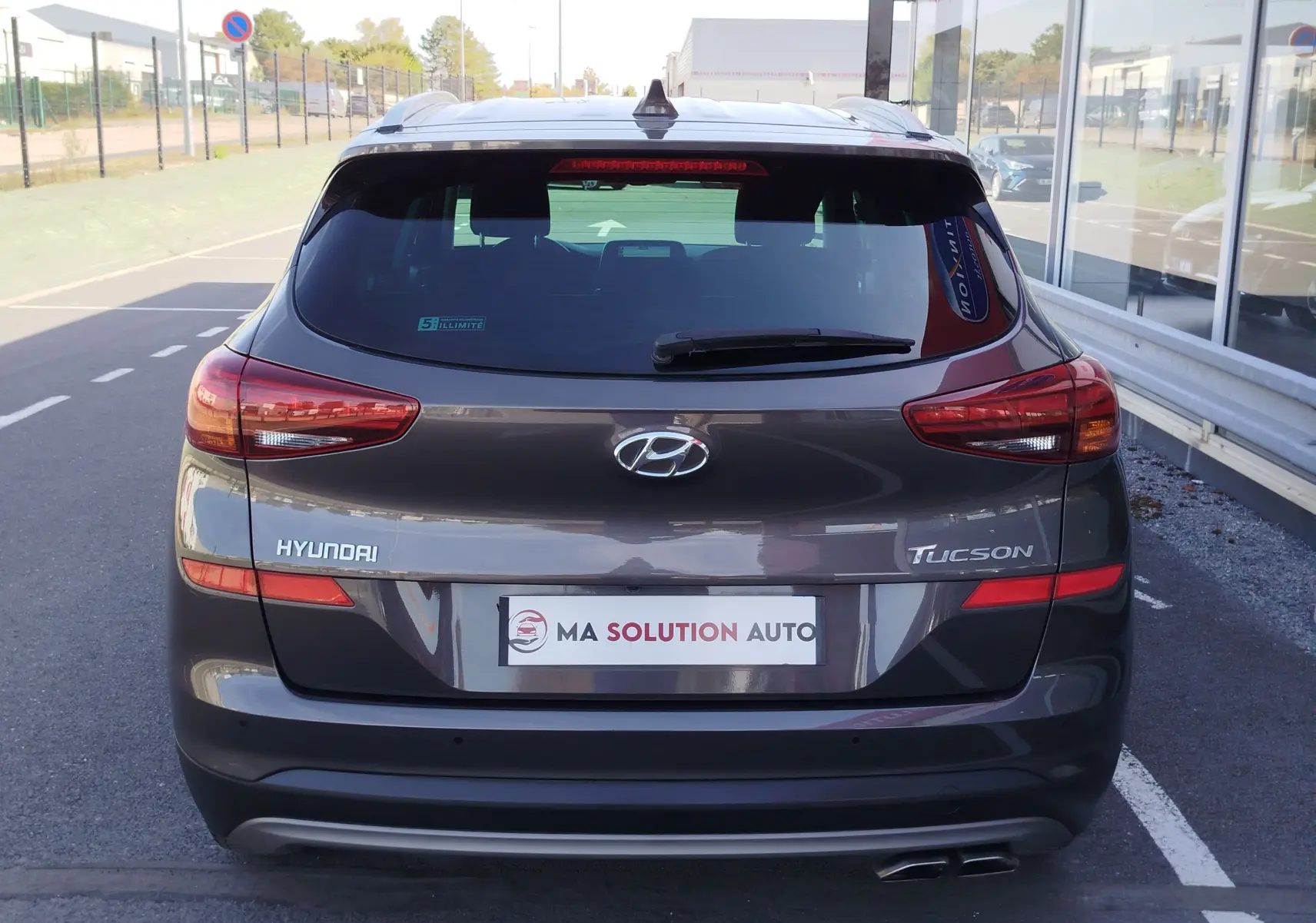 Vue arrière d'un Hyundai Tucson gris micron 2019, avec feux arrière allongés et double sortie d'échappement visible.