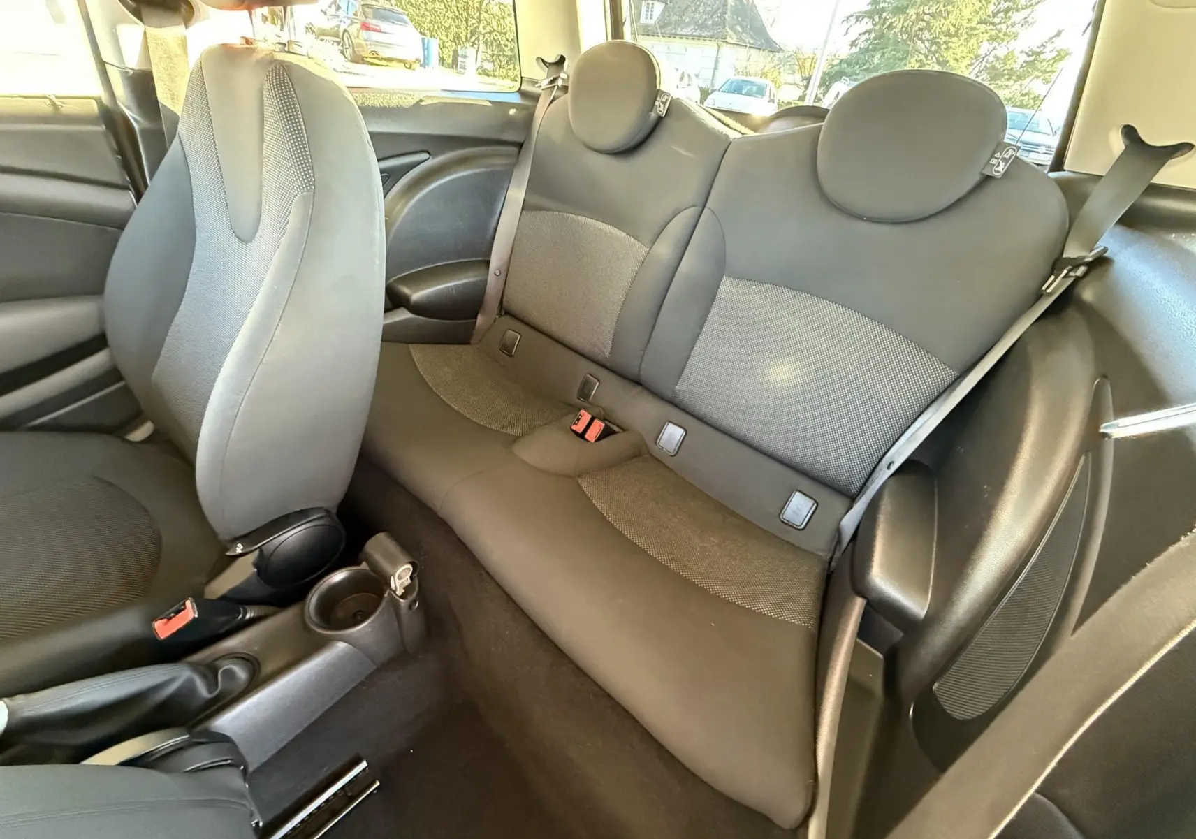 Vue intérieure de la banquette arrière et siège avant gris foncé d'une MINI Cooper 2007, tissu et plastique.
