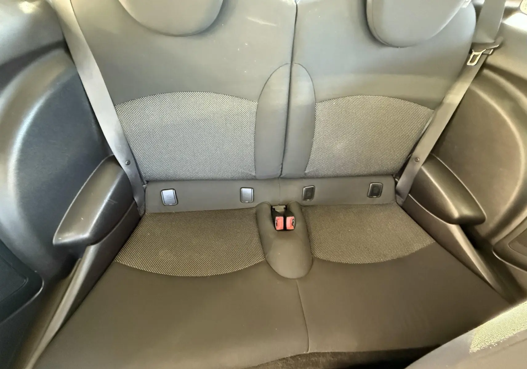 Banquette arrière en tissu gris et noir de la MINI Cooper 1.6 Ess 2007, vue de dessus, avec ceintures de sécurité visibles.