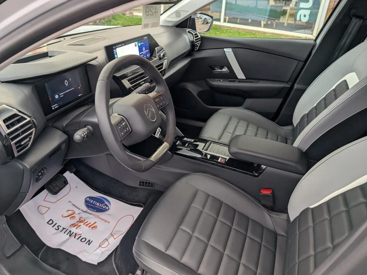 Intérieur avant droit de la Citroën C4 2025 blanc, avec sièges bicolores et tableau de bord numérique moderne.