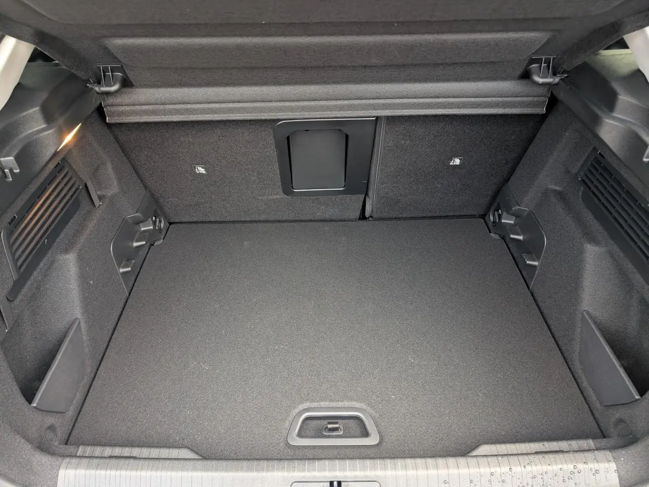 Coffre spacieux et propre de la Citroën C4 2025, vue intérieure arrière avec banquette rabattue et éclairage latéral.