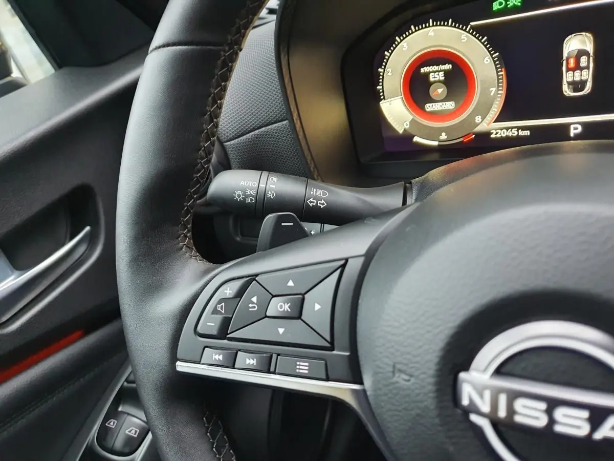 Vue rapprochée du volant noir et du tableau de bord digital du Nissan Juke 2025 avec commandes multifonctions.