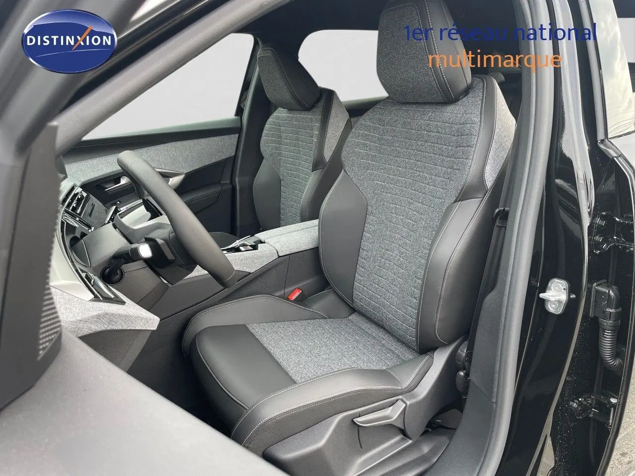 Intérieur du Peugeot 3008 Hybrid 2025 en noir perle métal, vue côté conducteur sur sièges tissu et cuir gris.