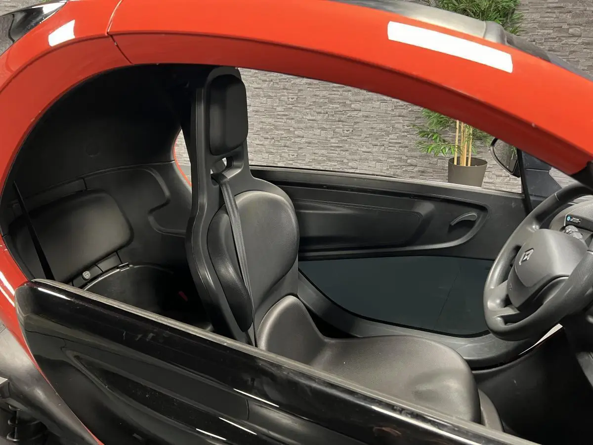 Intérieur côté gauche de la Renault Twizy orange 2019, avec siège noir et volant visible au premier plan.