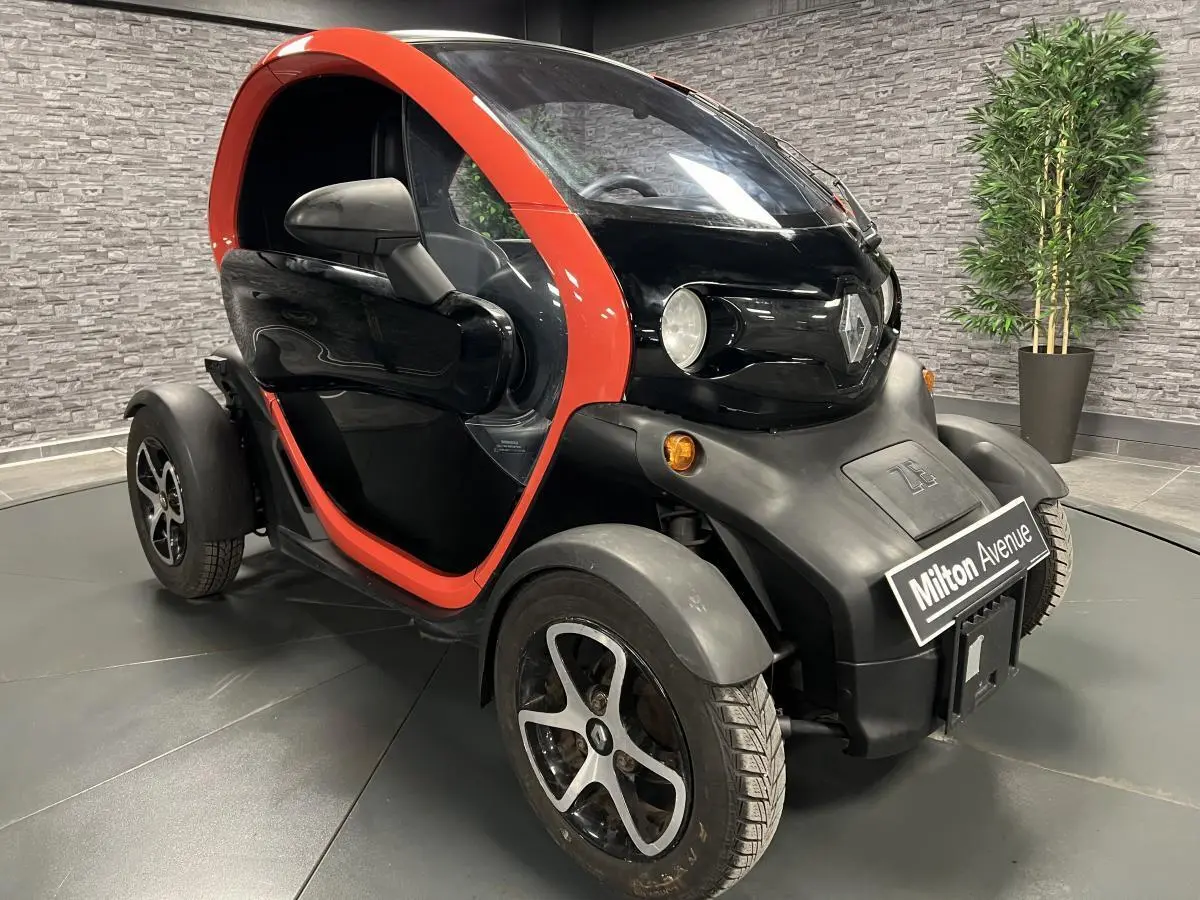 Vue 3/4 avant droite d'une Renault Twizy Intens 2019 orange avec portes élytre et jantes noires.