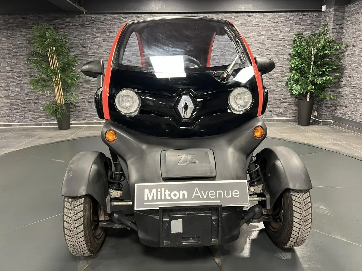 Vue de face d'une Renault Twizy Intens 2019 orange avec logo Renault et feux ronds dans un showroom.