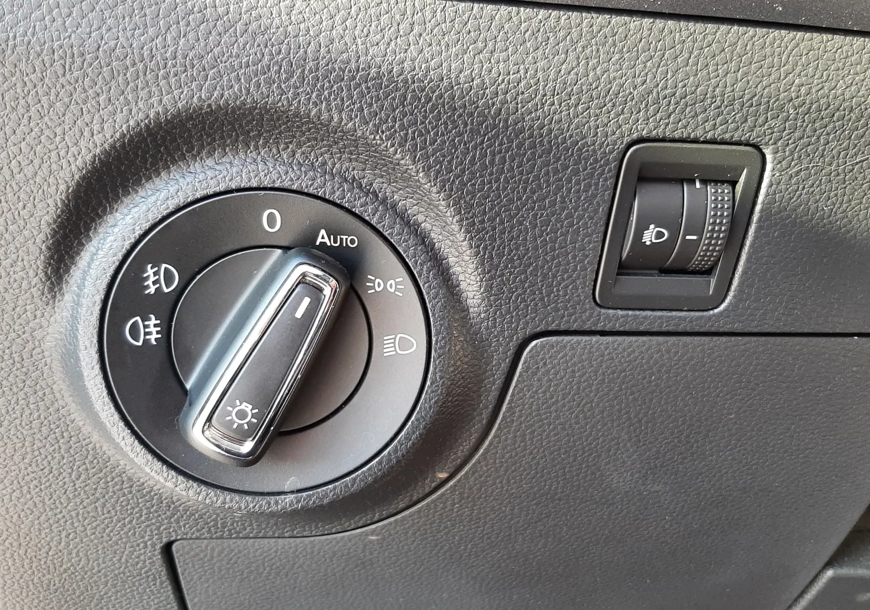 Gros plan sur le bouton de commande des phares et réglage d'intensité dans l'habitacle gris du SEAT Arona 2019.