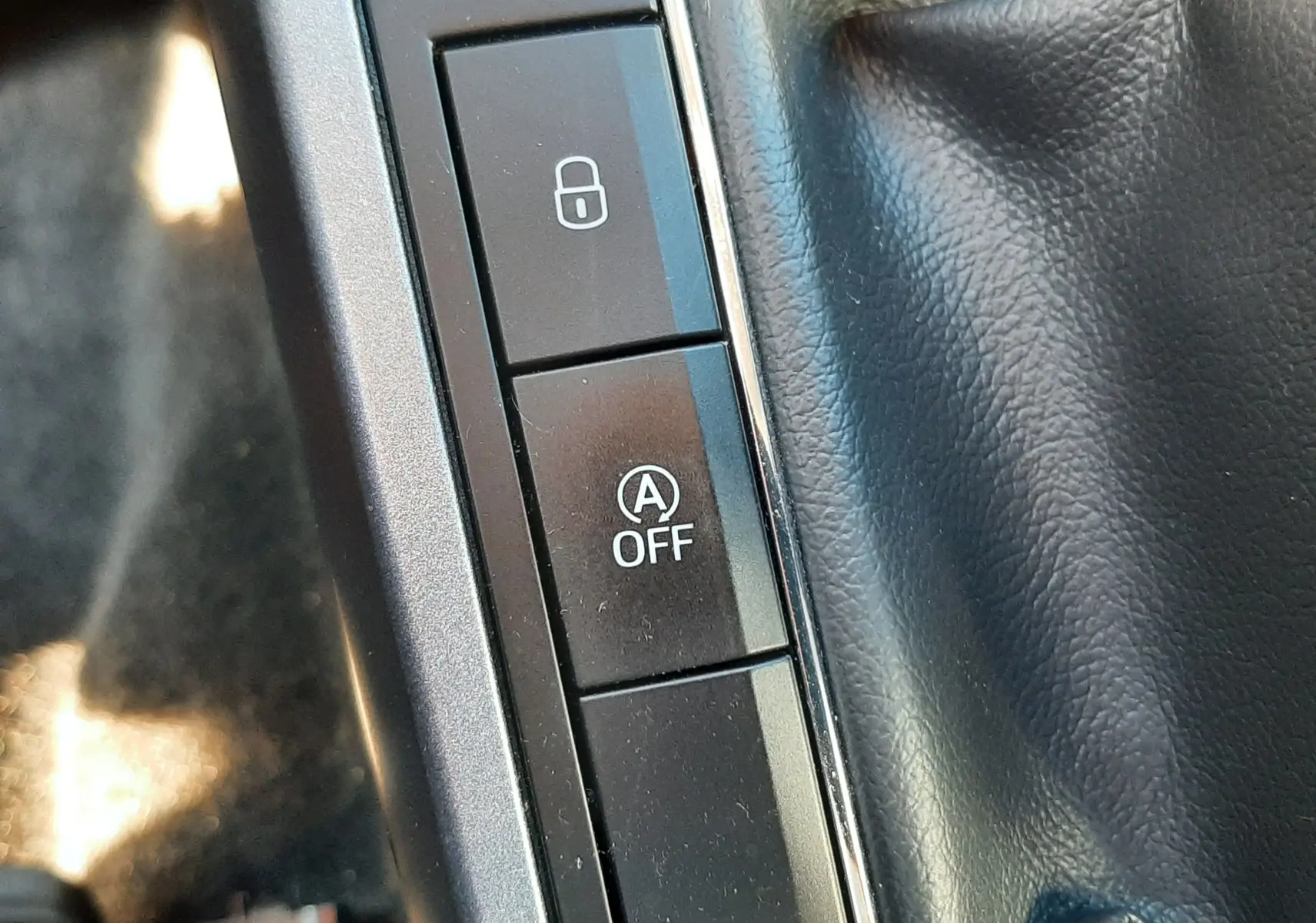 Gros plan sur les boutons de commande près du levier de vitesse en cuir noir dans le SEAT Arona gris Magnetic 2019.